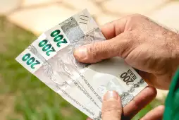 uma pessoa segurando notas de 200 reais para representar os Bancos que fazem empréstimo para negativados